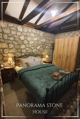 a bedroom with a green bed and a stone wall at Panorama Stone Houses - Skadar Lake in Cetinje