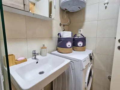 a bathroom with a sink and a washing machine at Blanc 1664 in Podgorica
