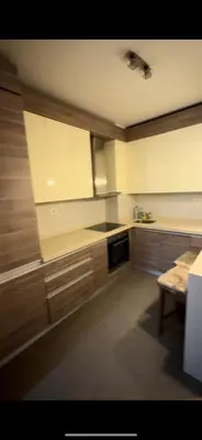 a kitchen with wooden cabinets and a table in it at Aida apartment City kvart in Podgorica