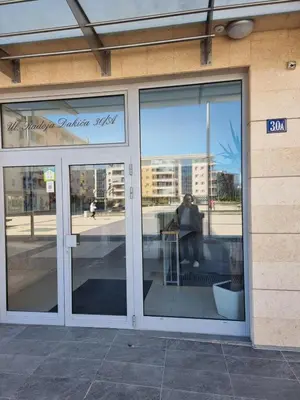 a store front with a reflection of a person in the window at Aida apartment City kvart in Podgorica