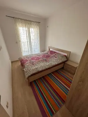 a small bedroom with a bed on a colorful rug at Marija apartment City kvart in Podgorica