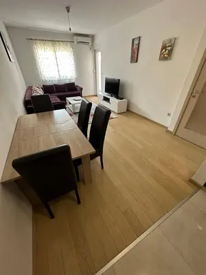 a living room with a table and chairs and a couch at Marija apartment City kvart in Podgorica