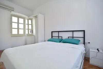 a white bedroom with a large bed with blue pillows at PERFECT OLD TOWN SPOT in Budva in Budva