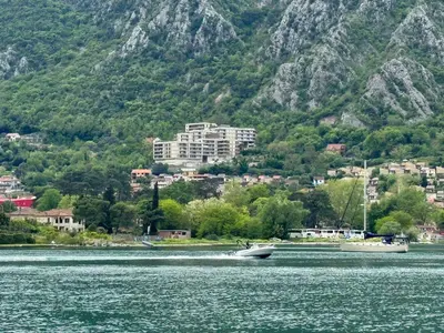 a boat on the water in front of a mountain at Sea Glass Kotor Bay in Škaljari