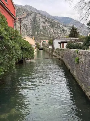 a river in a town with mountains in the background at Sea Glass Kotor Bay in Škaljari