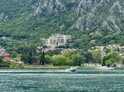a boat in a body of water with a mountain at Sea Glass Kotor Bay in Škaljari