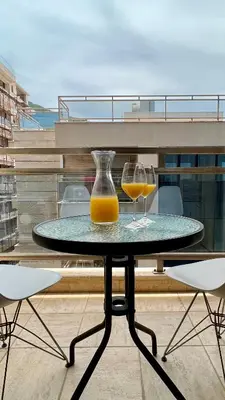 a glass vase and two glasses of orange juice on a table at Four Views By The Sea Apartments in Budva