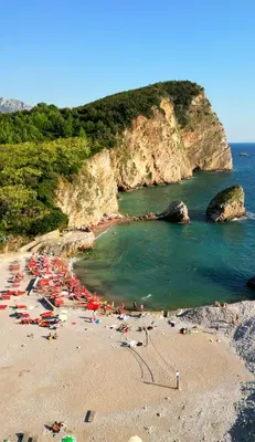 a beach with umbrellas and people on the sand at Four Views By The Sea Apartments in Budva