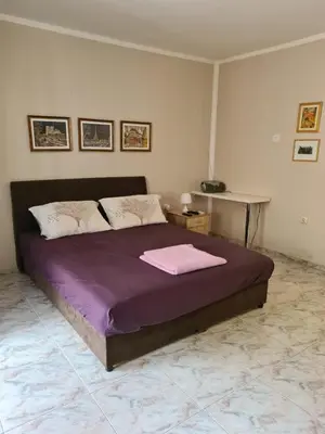 a bedroom with a bed with purple sheets and a table at Apartman Zvjezdana Dolina in Budva