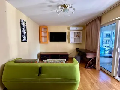 a green couch in a living room with a television at Apple apartment Petrovac in Petrovac na Moru