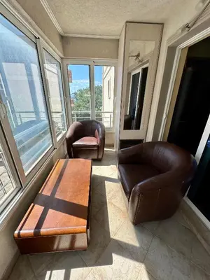 two leather chairs and a table in a room with windows at Apple apartment Petrovac in Petrovac na Moru