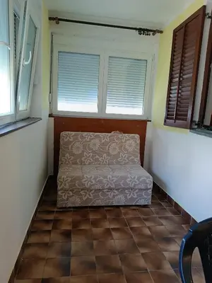a bed in a room with two windows and a tiled floor at Mira i Ola Apartman in Budva