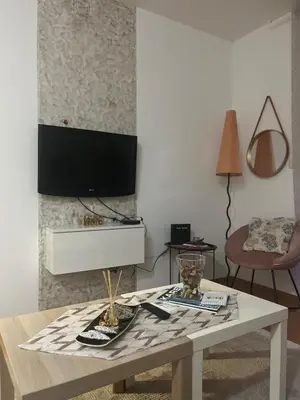 a living room with a table and a tv on a wall at Renta Slatki kutak in Podgorica