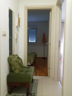 a living room with a green chair and a bedroom at Renta Slatki kutak in Podgorica