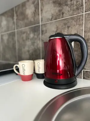 a red coffee pot sitting on a counter next to two cups at My Choice in Budva