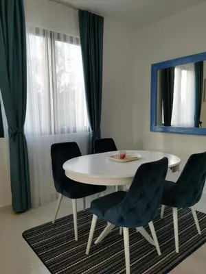 a dining room with a white table and blue chairs at Visnjeva Gardens in Višnjevo