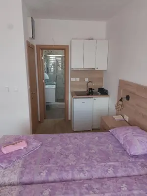 a bedroom with a bed and a kitchen with a sink at Apartmani Knezevic in Bar
