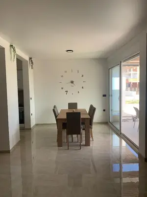 a dining room with a table and a clock on the wall at Bungalow Cleo in Donji Štoj
