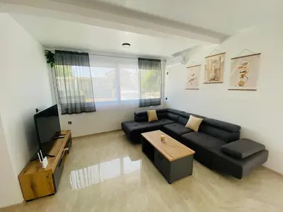 a living room with a black couch and a television at Bungalow Cleo in Donji Štoj