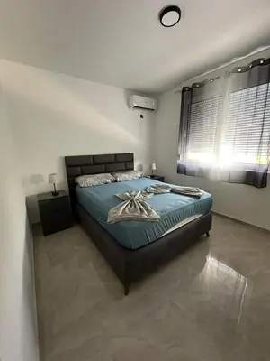 a bedroom with a bed with blue sheets and a window at Bungalow Cleo in Donji Štoj