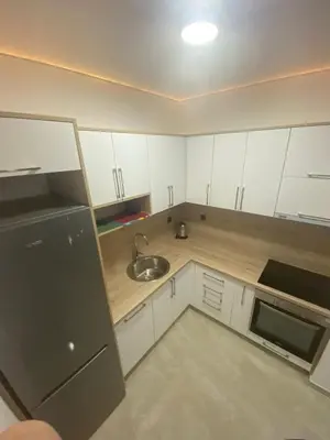 a kitchen with white cabinets and a sink and a refrigerator at Bungalow Cleo in Donji Štoj
