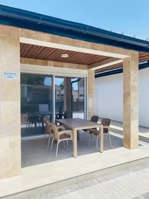 a wooden table and chairs on a patio with glass doors at Bungalow Cleo in Donji Štoj