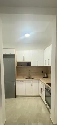 a kitchen with white cabinets and a stainless steel refrigerator at Bungalow Cleo in Donji Štoj
