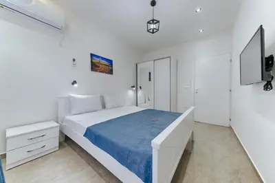 a white bedroom with a large bed with blue sheets at Lux DAM Apartments in Bar