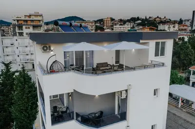 a white building with chairs and umbrellas on the balcony at Lux DAM Apartments in Bar