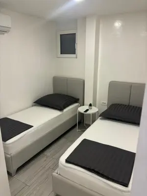 a bedroom with two beds and a small table at Maja Apartmani in Sutomore
