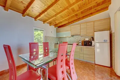 a kitchen with a glass table and red chairs at Villa Blue Bay in Kruče