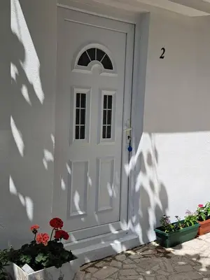 a white door with a window and some plants at Tinina Basta in Sutomore
