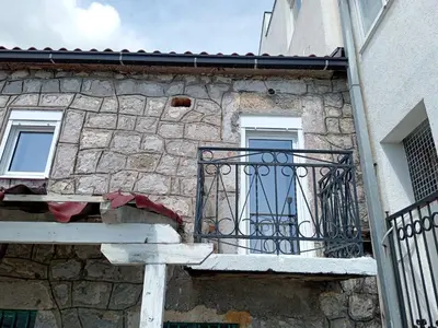 a stone building with a gate and a balcony at Apartmani Lakovic in Sutomore