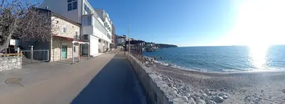 a sidewalk next to the ocean next to a building at Apartmani Lakovic in Sutomore
