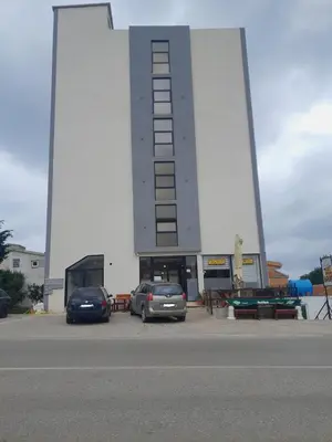 two cars parked in a parking lot in front of a building at Dubrava Czarnogóra in Dobra Voda