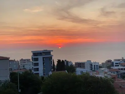 a sunset over a city with the ocean and buildings at Dubrava Czarnogóra in Dobra Voda