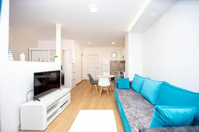 a living room with a blue couch and a table at Newly refurnished apartment with large garden in Budva