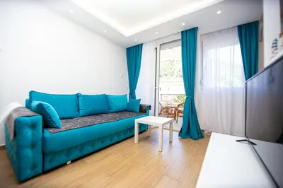 a blue couch in a living room with a window at Newly refurnished apartment with large garden in Budva