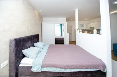 a bedroom with a bed with a purple blanket at Newly refurnished apartment with large garden in Budva