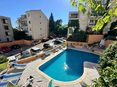 a swimming pool in a parking lot with parked cars at Sun Bay Petrovac in Petrovac na Moru