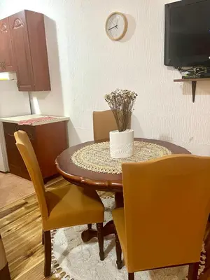 a dining room table with yellow chairs and a clock at Apartment Rumi Sutomore in Sutomore
