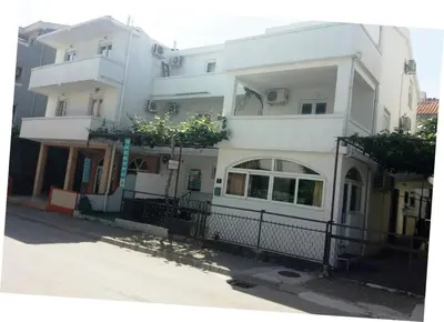 a large white building with a fence in front of it at Mirko Apartments Budva in Budva