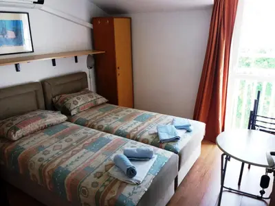 a bedroom with two beds and a table and a window at Mirko Apartments Budva in Budva