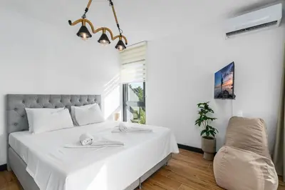 a bedroom with a large white bed and a chair at Royal Oasis Seaview - Sveti Stefan in Sveti Stefan