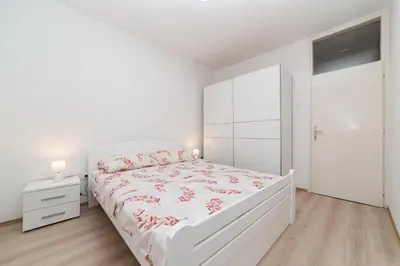 a white bedroom with a white bed and a white closet at Apartment Simanic in Budva
