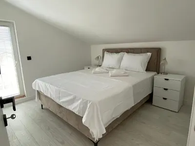 a white bedroom with a large bed and a window at Coastal Two Bedroom Comfort in Budva