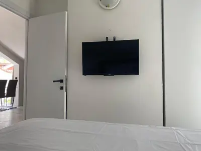a bedroom with a flat screen tv on a white wall at Coastal Two Bedroom Comfort in Budva