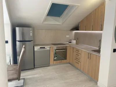 a kitchen with wooden cabinets and a stainless steel refrigerator at Coastal Two Bedroom Comfort in Budva