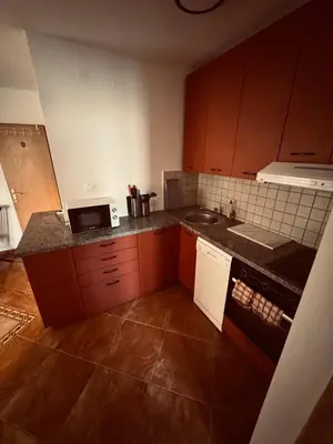 a kitchen with brown cabinets and a counter top at Garden Apartments Budva in Boreti