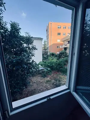 a window with a view of a yard with a building at Garden Apartments Budva in Boreti